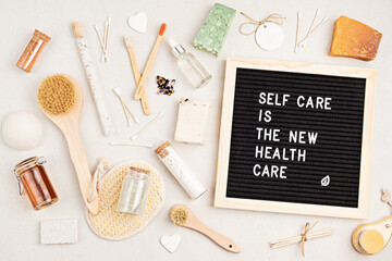 Self care is the new health care. Motivational quote on black letter board with variety of organic body and face care products. Natural homemade eco friendly beauty products