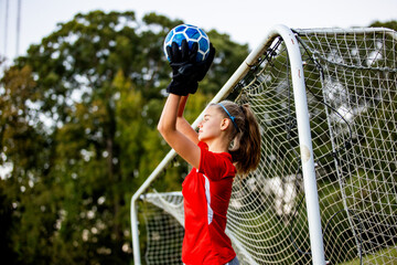 Teenage girl playing goalie on soccer field