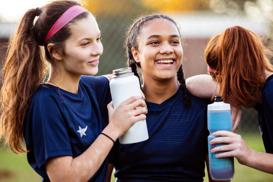 Female soccer players drinking water on field