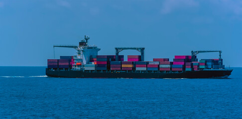 A fully loaded container ship at sea approaching the Singapore Straits in Asia in summertime