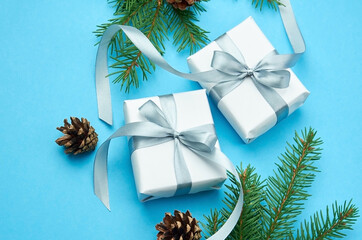 Christmas gift boxes with spruce branches and cones on blue paper background