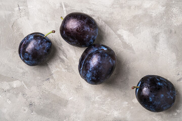 Fresh ripe plum fruits with water drops on stone concrete background, top view close up