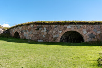 Military architecture of Suomenlinna bastion fortress at Kustaanmiekka island and bright green lawn in front.
