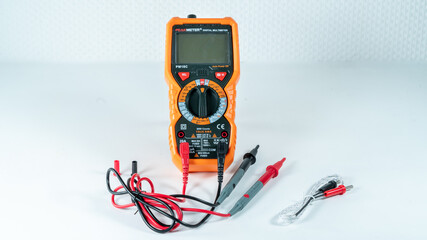 Orange and black multimeter, on white background, object for measuring electricity and temperature