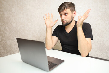 a man with a beard is working on a laptop in surprise