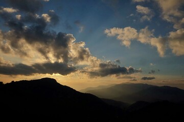 Blurred silhouette sunrise over a mountain against blue sky white clouds in the morning with a shadow of high mountains in Chiangmai,Thailand