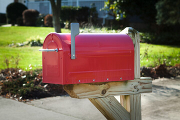 Red rural mailbox on a wooden post with flag up
