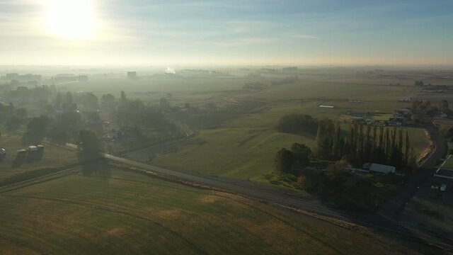 Aerial at sunrise with morning mist on small agricultural town in rural America
