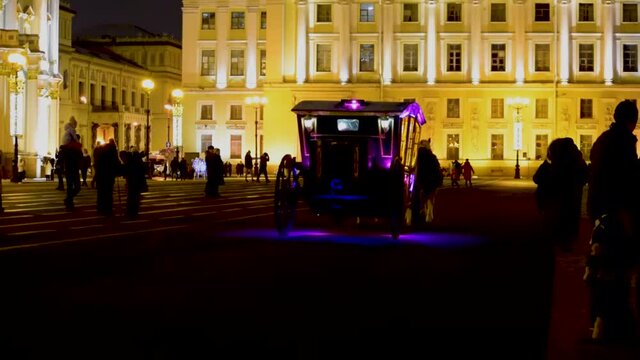 Outdoor view of Tsar horse carriage in front of Winter Palace landmark tourist attraction at eveningtime. Coach on the square and womans in traditional Russian clothes.