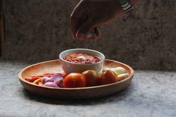 Indonesian traditional extra spicy chili sauce with ingredients, chilies, onions, garlic, salt, and tomatoes