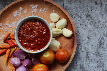 Indonesian traditional extra spicy chili sauce with ingredients, chilies, onions, garlic, salt, and tomatoes