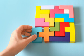 Multicolored puzzle, hand and cubes on a blue background