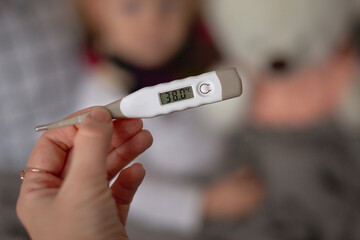 digital thermometer with a high temperature of 38 degrees holds in your hand.