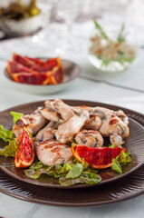 Grilled Frog Legs Garnished with Blood Orange Slices and Fresh Lettuce