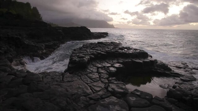 Waves crash on rocky coastline in Kauai, wide