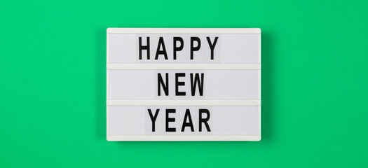 Happy new year text in a light box on green background