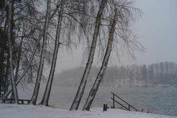 Blizzard in the touristic resort. White snowy Russian winter coming. River bank had been covered by snow. Weather forecast - snow with rain. Concept of  the beauty in nature despite the bad weather.