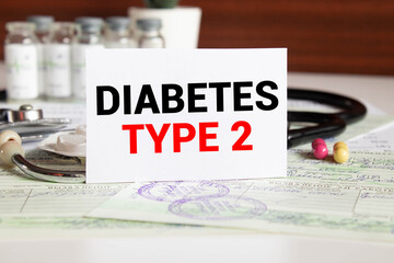 Word TYPE 2 DIABETES written on a book with gift boxes against wooden table.