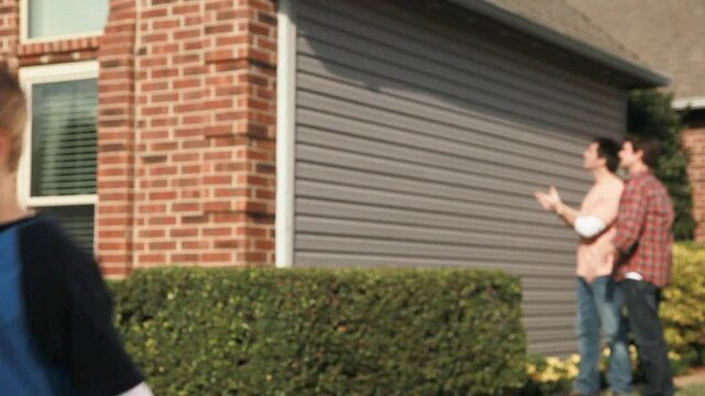 Confused Caucasian boy leaving as two men behind him discus house