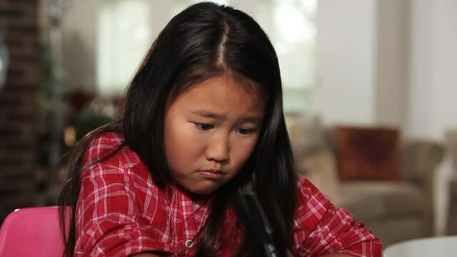 Close up of confused Chinese girl shrugging then writing