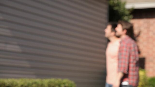 Confused Caucasian boy leaving as two men behind him discus house