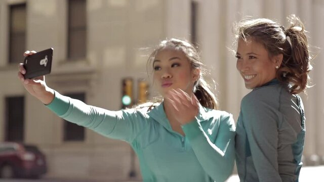 Women using cell phone to take self-portraits in city