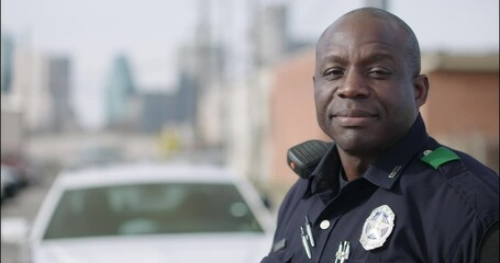 Police officer standing at police car and smiling