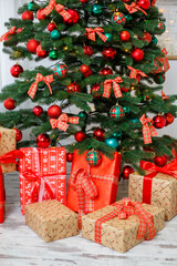 Christmas background: green tree decorated with red and green balls, Christmas decorations, yellow garlands. New Year. Gifts under the tree for the holiday
