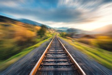 Railroad in mountains with motion blur effect at sunset in autumn. Industrial landscape with...