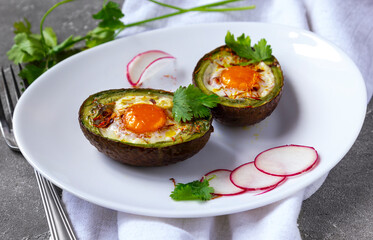 Baked eggs in avocado Boats with radish on white plate