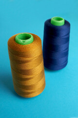 two large new skeins of blue and orange denim thread stand on a blue background side view