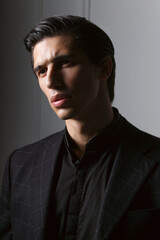 Fototapeta premium Closeup portrait of a handsome business man dressed in black suit against a dark grey background.