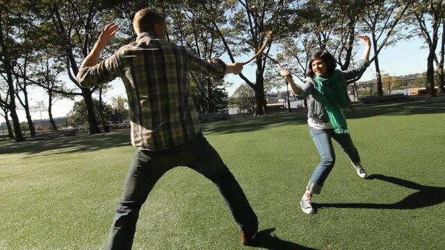 Couple having fake sword fight in park, New York City, New York, United States