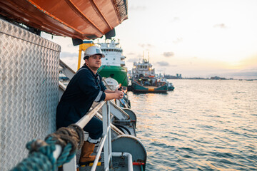 Marine Deck Officer or Chief mate on deck of offshore vessel or ship , wearing PPE personal protective equipment - helmet, coverall. Ship is on background