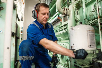 Marine engineer officer controlling vessel engines and propulsion in engine control room ECR. Ship...
