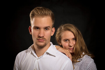 Young beautiful couple studio portrait on black background.