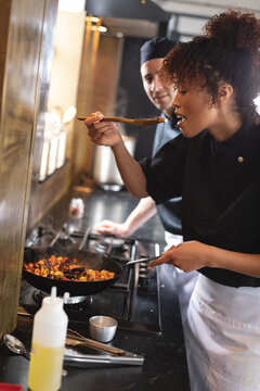 Female african american chef tasting food while cooking at restaurant kitchen