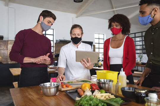 Female chef and divserse group wearing face masks in kitchen