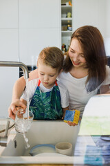 Mother and son wash dishes together.