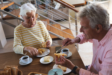 Happy senior caucasian couple having breakfast at home