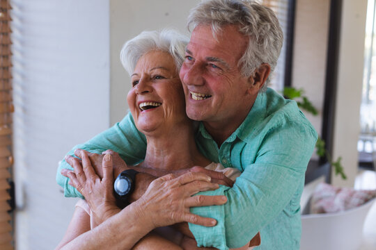 Happy senior caucasian couple at home embracing and smiling - Powered by Adobe