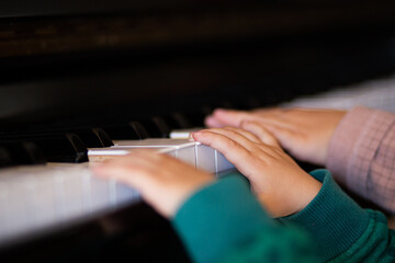 Fototapeta na wymiar Baby hands playing a black piano keyboard close up still