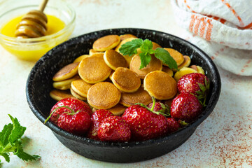 Trendy food - pancake cereal. Mini cereal pancakes with strawberries in iron frying pan