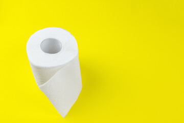 Top view of white toilet paper rolls on yellow background with copy space.