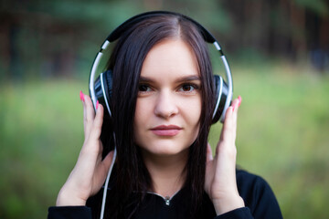 close-up portrait of young woman with headphones on her ears looking at camera
