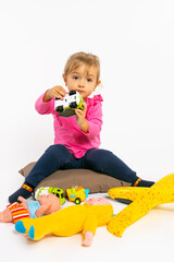 Toddler girl plays with boy toys and looks at the camera. Gender stereotypes.