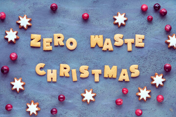 Text Zero Waste Christmas made from cookies. Xmas top view. Minimal design with star cookies and fresh cranberry, Natural Christmas decorations on grey textured aged sbackground.