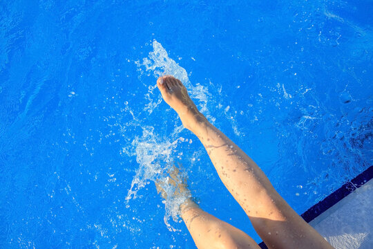 cropped young european woman kicks in the pool splashes water. Concept, carefree, summer, vacation. Copy space. View from above