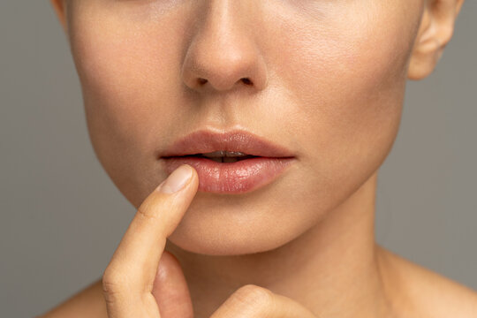 Close Up Of Woman Applying Moisturizing Nourishing Balm To Her Lips With Her Finger To Prevent Dryness And Chapping In The Cold Season. Lip Protection. 