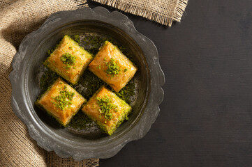 Traditional turkish dessert antep baklava with pistachio on rustic table,  ramadan or holiday desserts concept